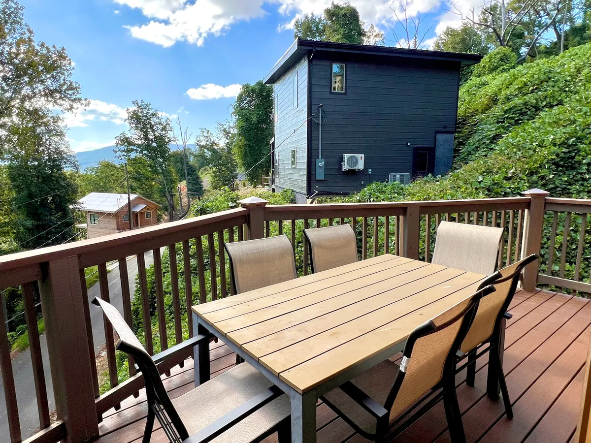 An outdoor dining area featuring a wooden table and chairs set amidst lush greenery. The setting encourages al fresco meals, group gatherings, and relaxation, with expansive views that invite guests to unwind together after a day of exploring local attractions.