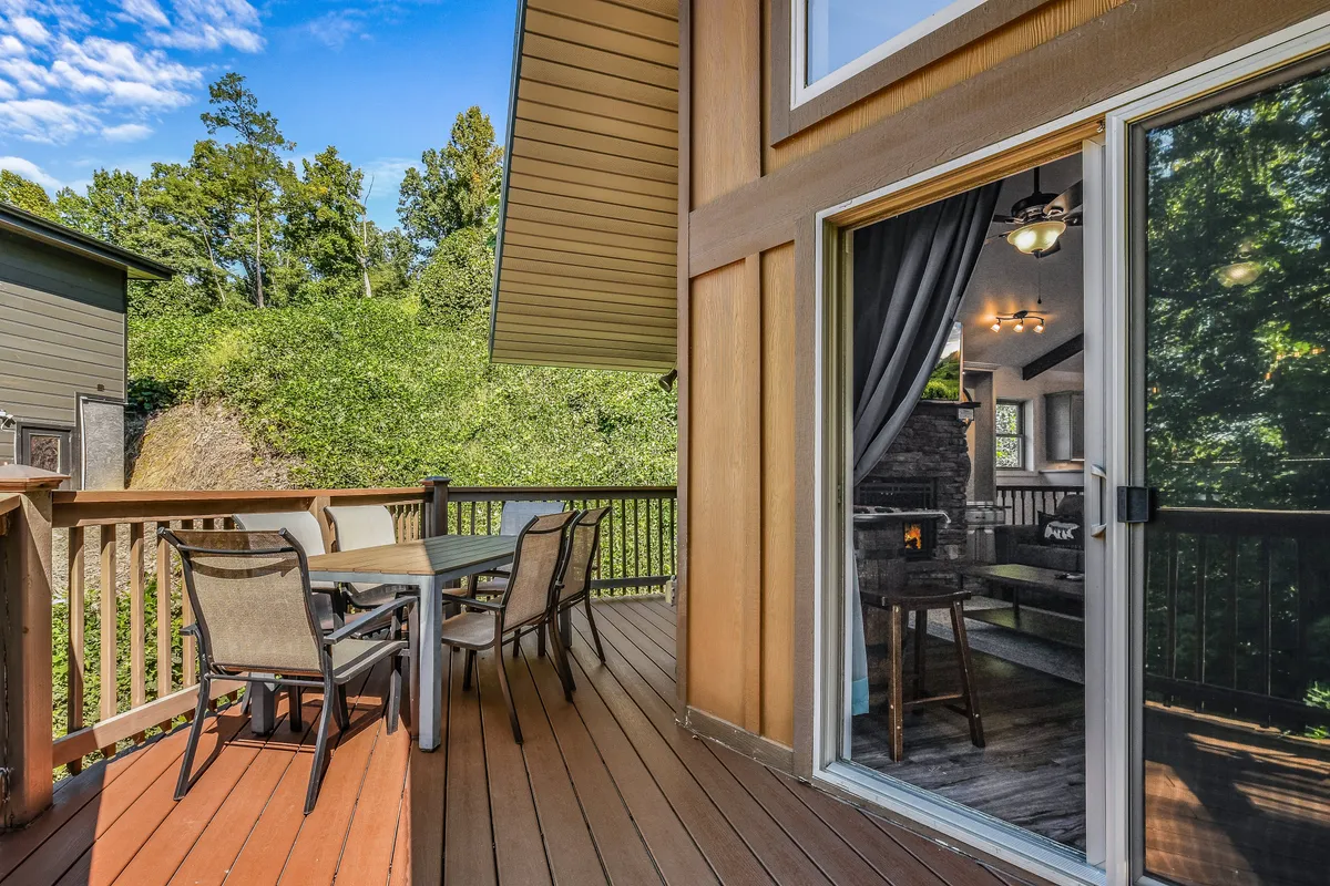 An inviting exterior deck with comfortable outdoor furniture, a sliding glass door opening to the interior, and greenery beyond. The scene bridges the indoors and outdoors, suggesting relaxation or dining after a day of exploration.