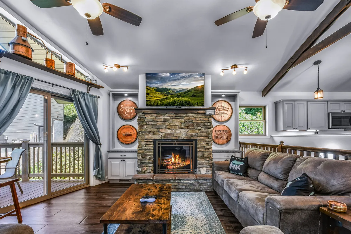 A warm living room scene featuring a fireplace, comfortable couch, television, and a wooden coffee table. The space is designed for relaxing, gathering, and enjoying movie nights or games together.