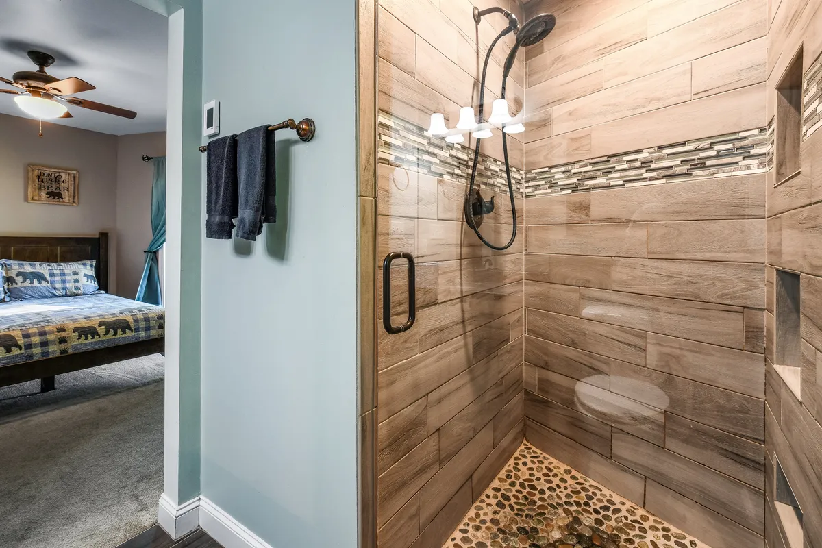 This bathroom image spotlights a rain showerhead, a textured tile wall, and a pebble floor—creating a spa-like, rejuvenating atmosphere perfect for unwinding.